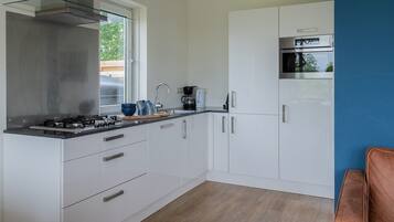 Een koelkast, een kookplaat, een waterkoker, eettafels