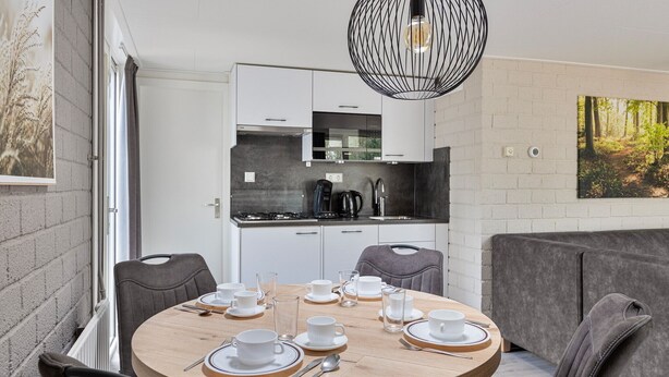 A modern kitchen with white cabinets and a black coffee machine. - Semi-detached bungalow for 2 persons (Kootwijk)