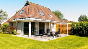 A house with a covered patio, a brick exterior, and a sloped roof.