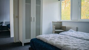 Un dormitorio con una cama, una silla y un armario.