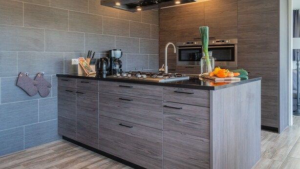 Una cocina moderna con una isla central, armarios de madera oscura, una campana extractora de acero inoxidable y un horno empotrado.
