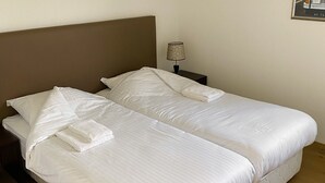 A double bed with white linens, a nightstand with a lamp, and a framed picture on the wall. - Schoonhoven Wellness 6 (Hollandscheveld)