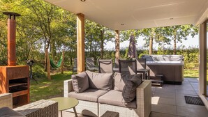 Un patio exterior con sofá, sillas, una parrilla y un jacuzzi.