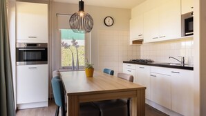 Una cocina moderna con armarios blancos, una mesa de comedor de madera y un reloj en la pared.