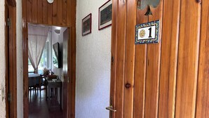 Una puerta de madera con un cartel con el número 1, un ventanal pequeño y un timbre.