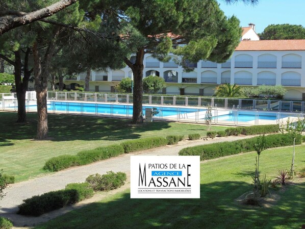Un hôtel doté d’une piscine, entouré d’arbres, et un bâtiment agrémenté de balcons.