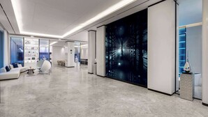 A modern hotel lobby with a spacious layout, a central seating area, and a large digital art display on the wall. - Microtel by Wyndham Xishuangbanna Mengle (Xishuangbanna Dai)
