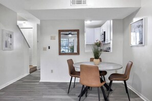 A modern dining area with a round table, four chairs, and a vase with flowers.