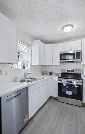 A modern kitchen with white cabinets, stainless steel appliances, and a dishwasher.