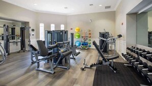 Een fitnessruimte met diverse trainingsapparaten, waaronder krachttrainingsmachines en losse gewichten.