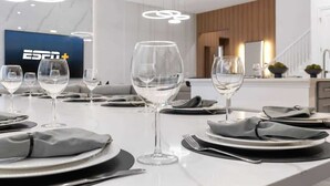 Un espace repas moderne avec une table en marbre, de la verrerie transparente et un mur servant de fond, sur lequel est affiché le logo d’ESPN+.