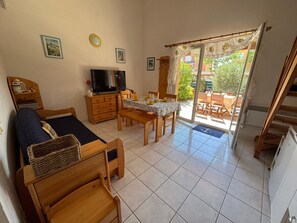 Una habitación con cama, televisión, mesa de comedor y vistas al exterior.