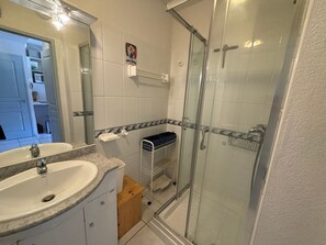 Baño con lavamanos, espejo, ducha y toallero.