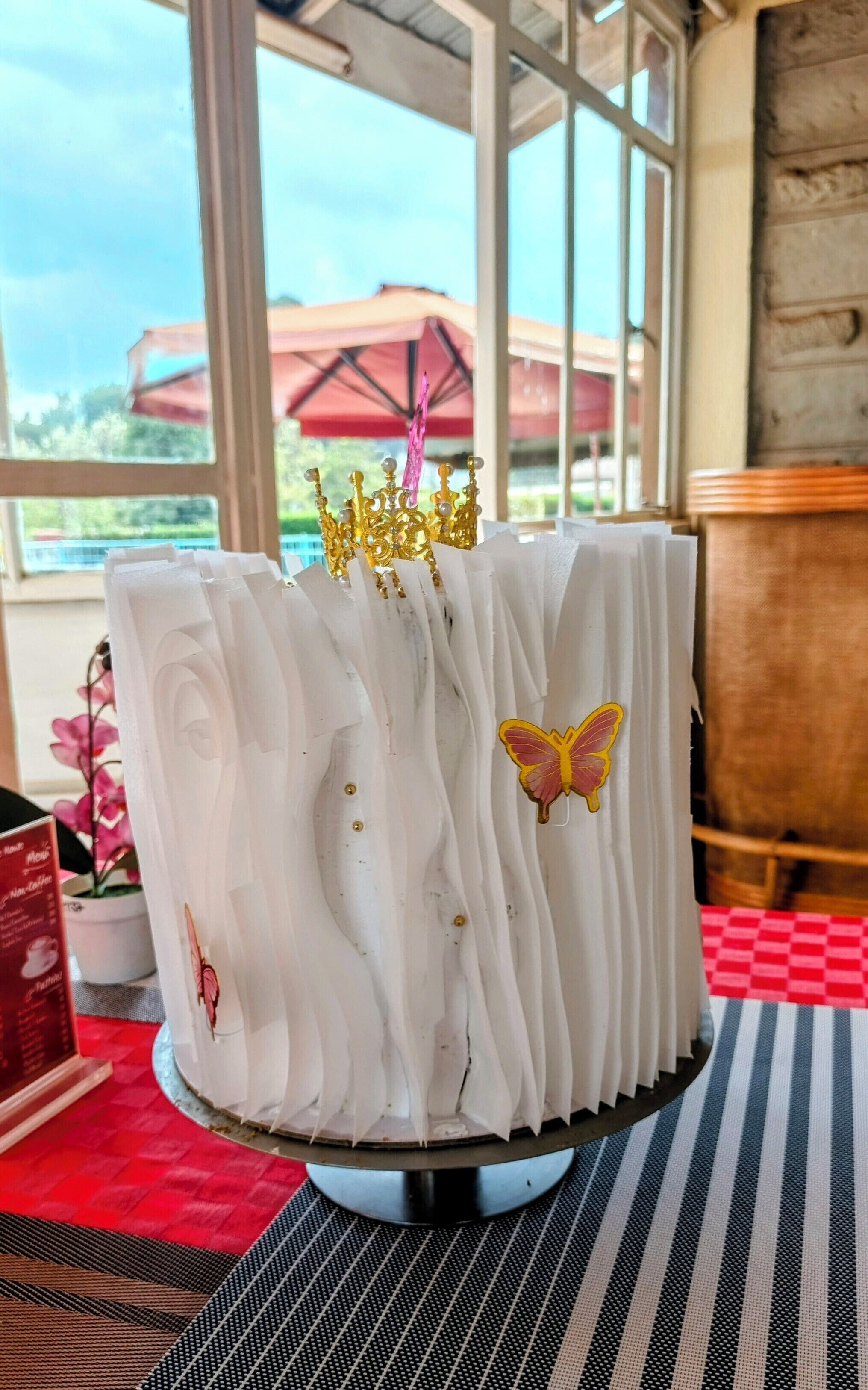 Un pastel con glaseado blanco y detalles decorativos sobre un pedestal.