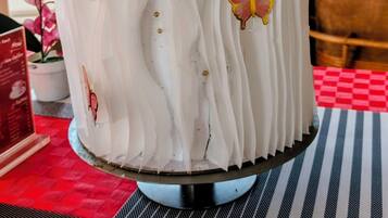 Un pastel con glaseado blanco y detalles decorativos sobre un pedestal.