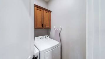 A laundry room with a white washing machine and wooden cabinets.