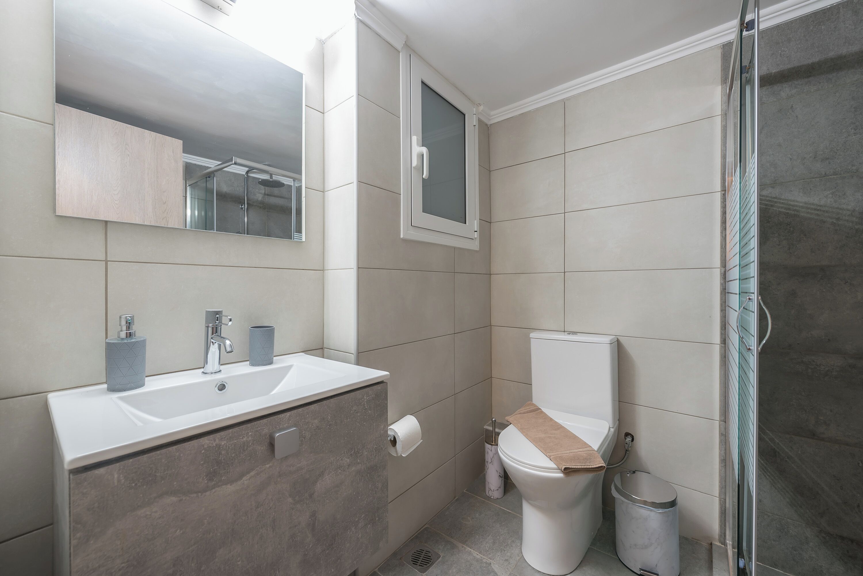 A modern bathroom with a white sink, a toilet, and a shower area.