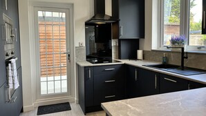 Una cocina moderna con armarios oscuros, estufa integrada y ventana con vistas al exterior.