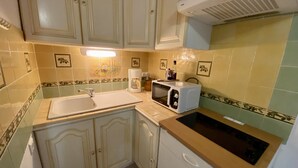 A kitchen with white cabinets, a sink, a microwave, and a stove. - T2 Mezzanine Villa - Air Conditioning - Veranda - Parking - Pool - 6 People (Fleury-Saint-Pierre-la-Mer)