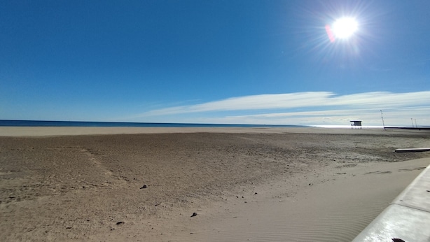 Ein Strand mit einem Rettungsturm und blauem Himmel.