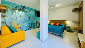 Une chambre avec un lit, un canapé, une fresque murale et un téléviseur.