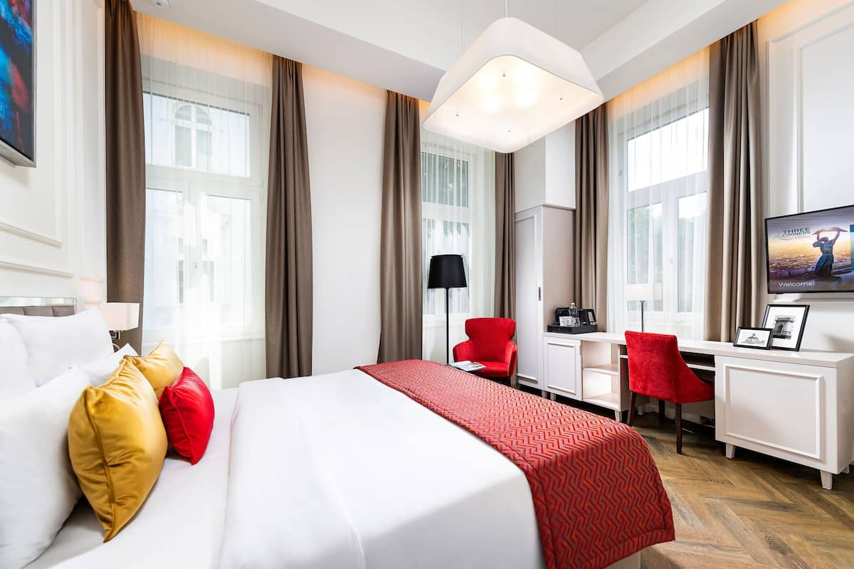 Ein Hotelzimmer mit Bett, Schreibtisch, Stuhl und Fernseher.