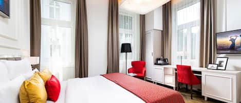 A hotel room with a bed, a desk, a chair, and a TV.
