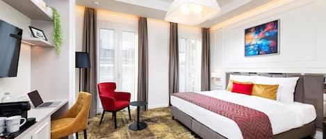 A hotel room with a bed, desk, chair, and a TV.