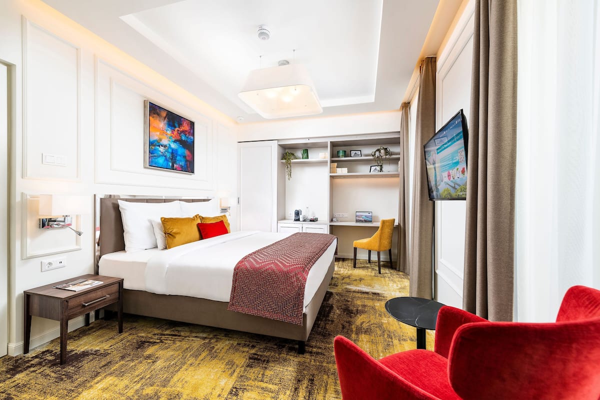 Ein Hotelzimmer mit einem Bett, einem Schreibtisch, einem Stuhl und einem Fernseher.