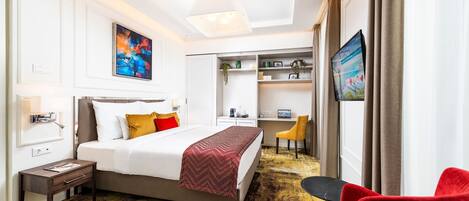 A hotel room with a bed, a desk, a chair, and a TV.