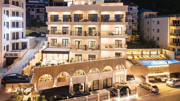 A multi-story hotel with balconies, a swimming pool, and a stone archway. - Hotel Exclusive  (Przno)