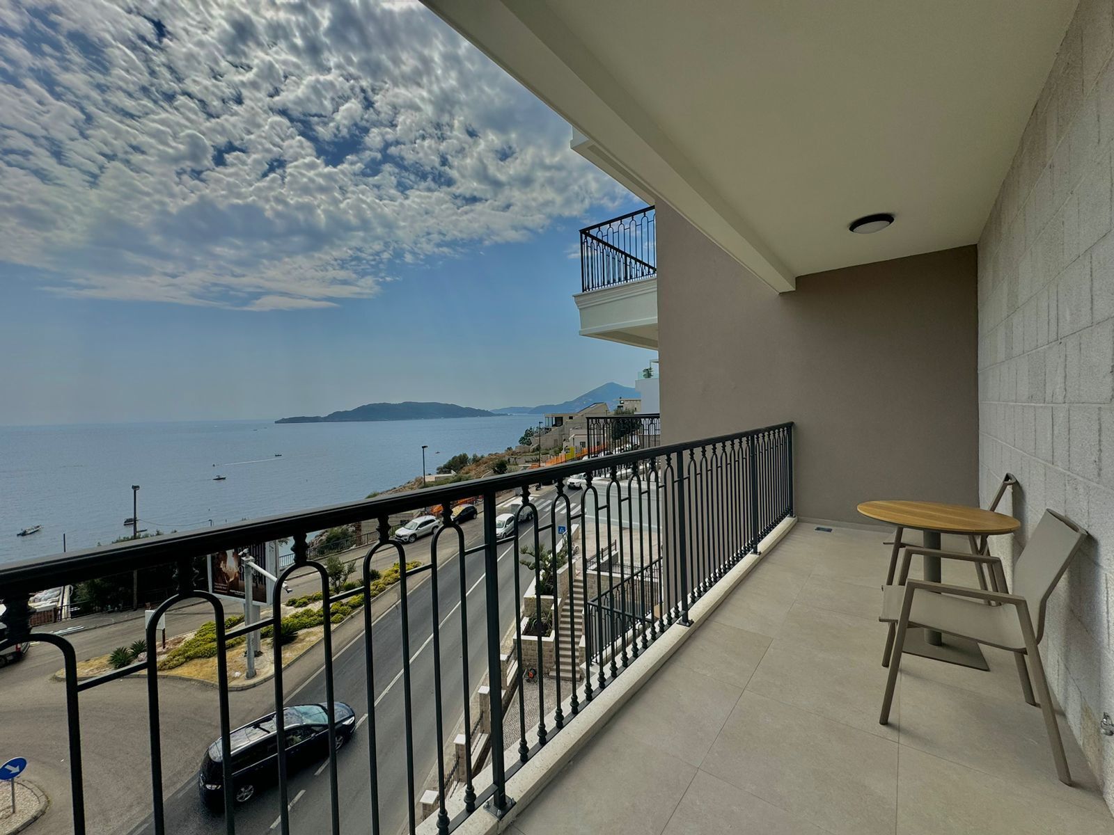 Un balcone con vista sul mare, un tavolo e delle sedie.