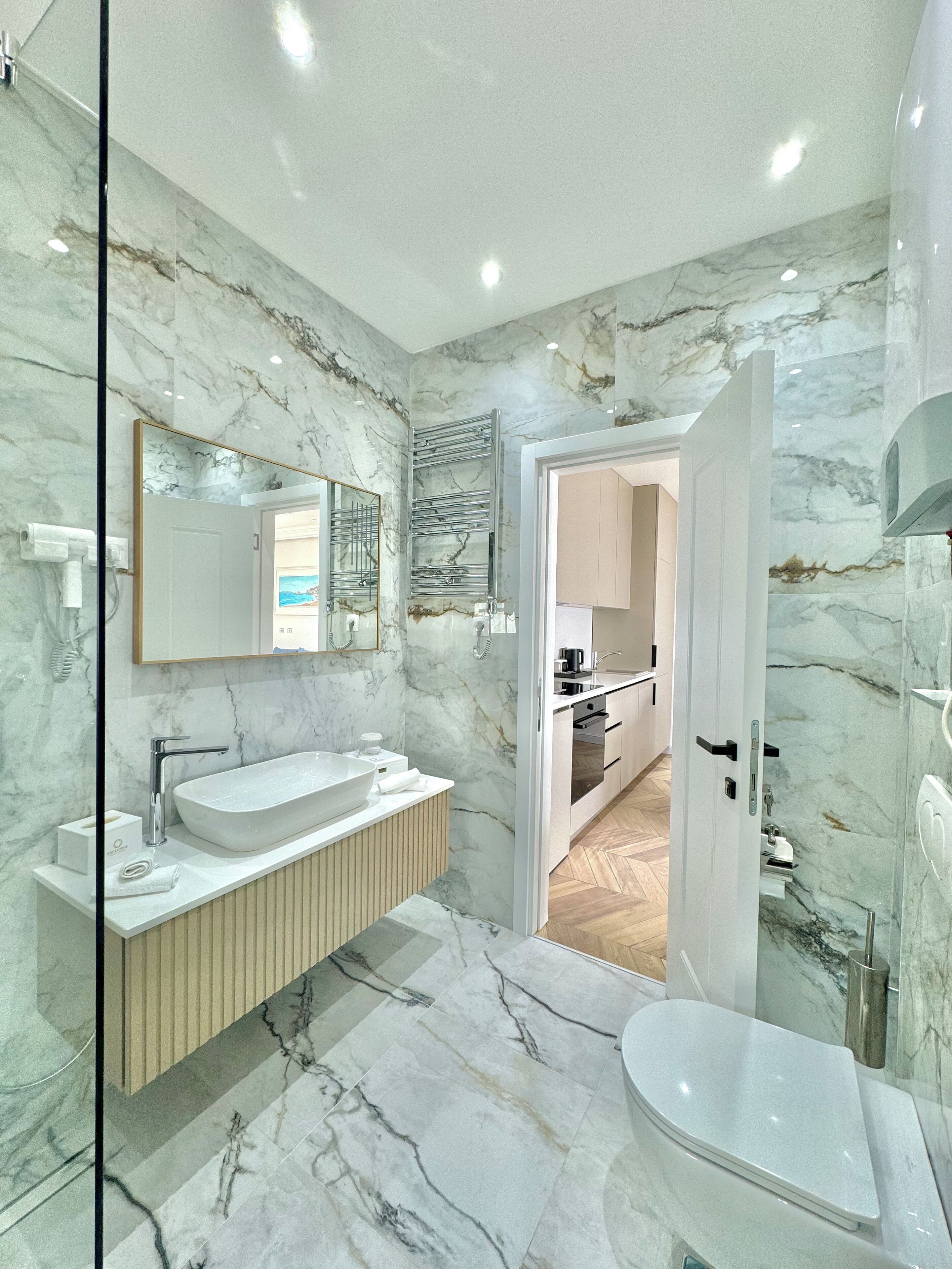 A modern bathroom with a marble backsplash, a freestanding sink, and a glass shower enclosure.
