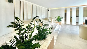 A modern reception area with a marble counter, seating, and a large plant. - Hotel Exclusive  (Przno)