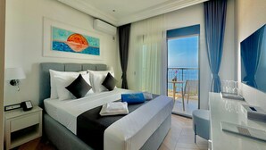 A hotel room with a bed, a nightstand, a desk with a chair, a painting on the wall, and a balcony with a view. - Hotel Exclusive  (Przno)
