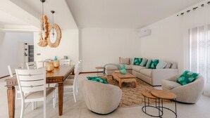 Ein modernes Wohnzimmer mit Essbereich, ausgestattet mit einer Sofagarnitur, einem Couchtisch und einem Esstisch mit Stühlen.