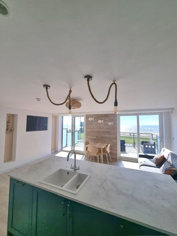 Una cocina moderna con una isla grande, un fregadero y un comedor con vista al mar.