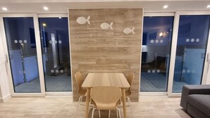 A modern dining area with a wooden table and chairs, a wooden accent wall with fish decorations, and glass doors leading to an outdoor deck.