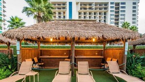 Un resort con cabañas de techo de paja, sillones de descanso y una zona de piscina.