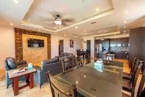 A modern living room with a glass-top dining table, leather sofas, and a stone accent wall.