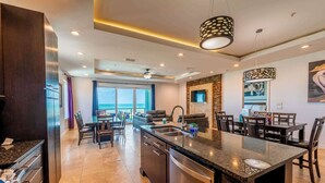 A modern kitchen with a central island, built-in appliances, and a dining area with a view. - Amberjack Oasis  (South Padre Island)
