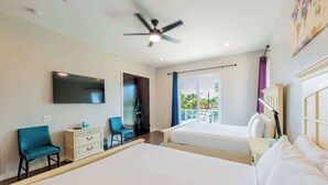 A hotel room with two beds, a ceiling fan, a TV, a desk with a chair, and a balcony with a view of the outdoors. - Amberjack Oasis  (South Padre Island)