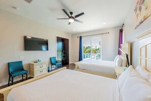 A hotel room with two beds, a ceiling fan, a TV, a desk with a chair, and a balcony with a view of the outdoors.