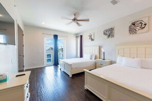 A hotel room with two beds, a ceiling fan, artwork on the walls, and a balcony with a view.