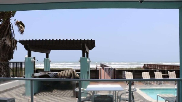Un balcon avec vue sur l’océan, une piscine et un espace salon extérieur.