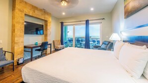 Une chambre d’hôtel avec un grand lit, un bureau avec une chaise, une télévision et un balcon avec vue.