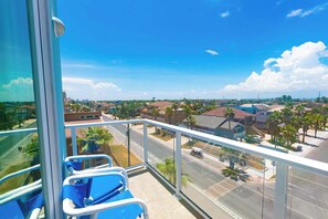 A balcony with a clear view of a residential area, including houses and palm trees.
