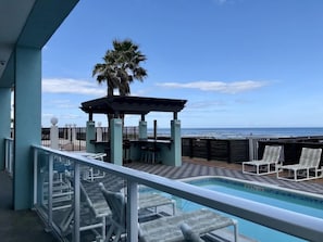 Un espace piscine avec des chaises longues, un coin salon abrité et une vue sur l’océan.