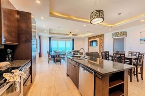 A modern kitchen with granite countertops, a dishwasher, and a dining area with wooden chairs and a large island.