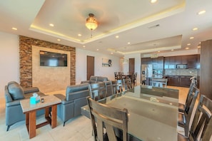 Un salon moderne avec une table à manger au plateau en verre, des canapés en cuir et un mur décoratif en pierre.